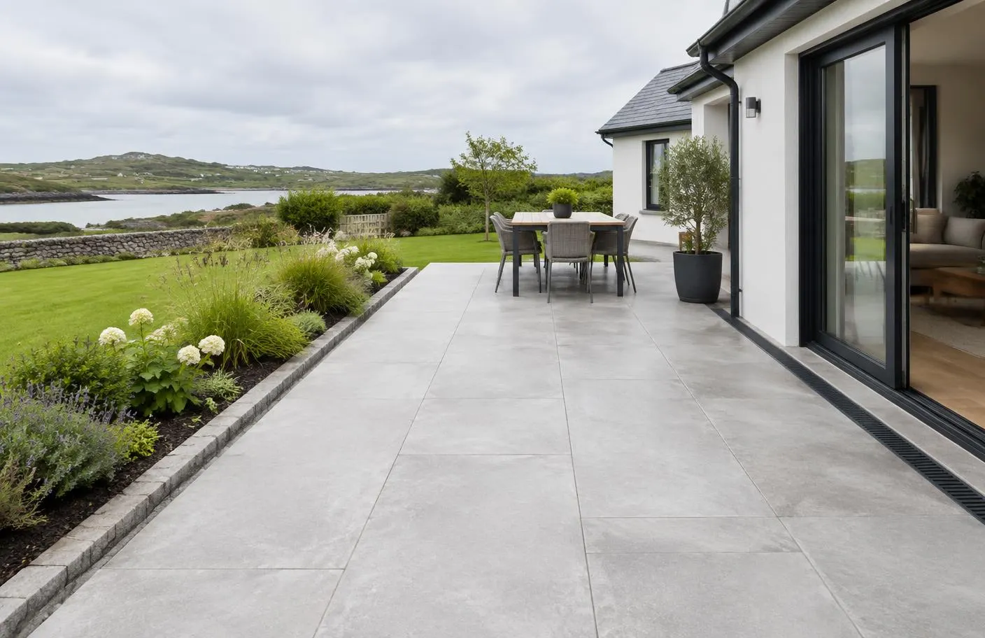 Outdoor porcelain patio beside a house with a drainage channel at the threshold